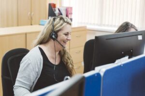 outsourced contact centre- lady on a headset taking a call in an office